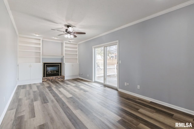 unfurnished living room featuring ceiling fan, wood finished floors, baseboards, ornamental molding, and a brick fireplace