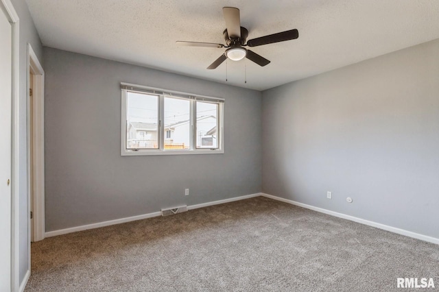 carpeted empty room featuring a textured ceiling, ceiling fan, visible vents, and baseboards