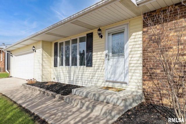 doorway to property with a garage and brick siding