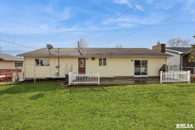 back of house featuring a patio area, a chimney, fence, and a lawn