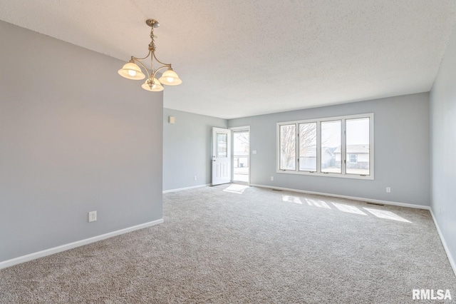 spare room with baseboards, a textured ceiling, carpet, and an inviting chandelier