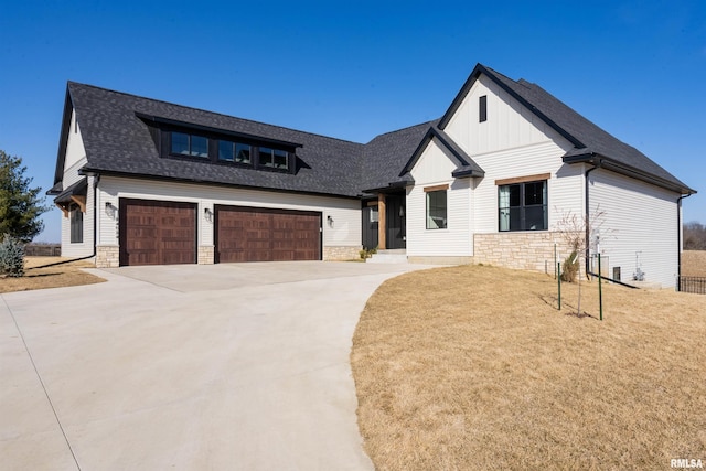 modern inspired farmhouse featuring a front yard, roof with shingles, concrete driveway, stone siding, and board and batten siding