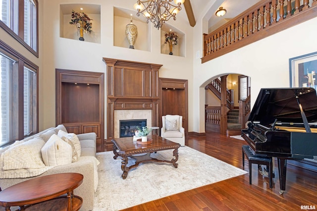 living room with plenty of natural light, arched walkways, dark wood finished floors, and a tiled fireplace