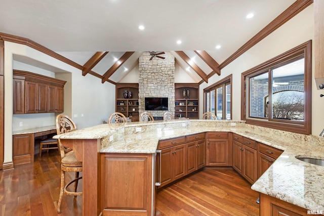 kitchen with light stone counters, dark wood-style flooring, built in desk, and lofted ceiling with beams