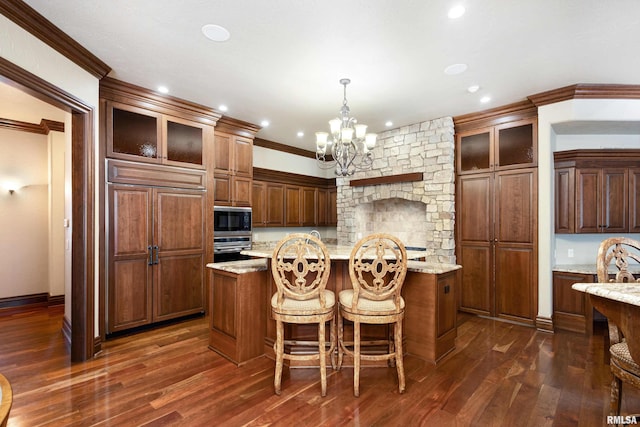 kitchen featuring built in appliances, ornamental molding, an island with sink, dark wood finished floors, and glass insert cabinets