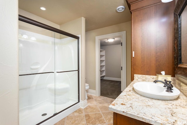 full bath featuring toilet, vanity, baseboards, a spacious closet, and a shower stall