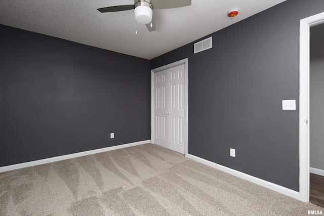 unfurnished bedroom with carpet, a closet, visible vents, a textured ceiling, and baseboards