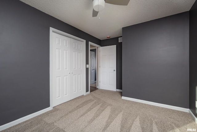 unfurnished bedroom with a textured ceiling, a closet, carpet, and baseboards