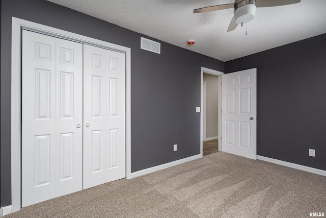 unfurnished bedroom featuring a textured ceiling, visible vents, baseboards, a closet, and carpet