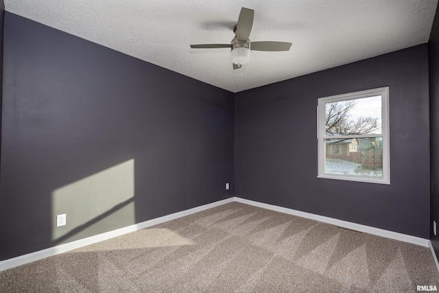 empty room with carpet floors, a textured ceiling, baseboards, and a ceiling fan