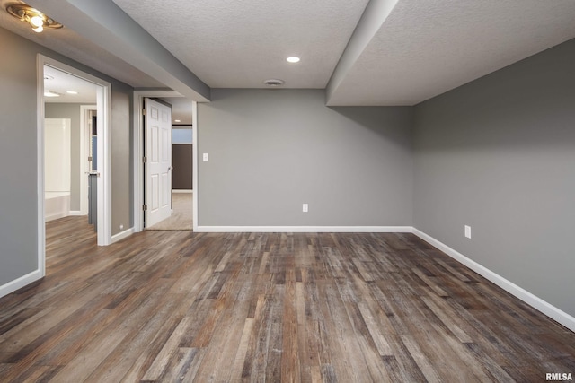 finished below grade area with dark wood-type flooring, a textured ceiling, and baseboards