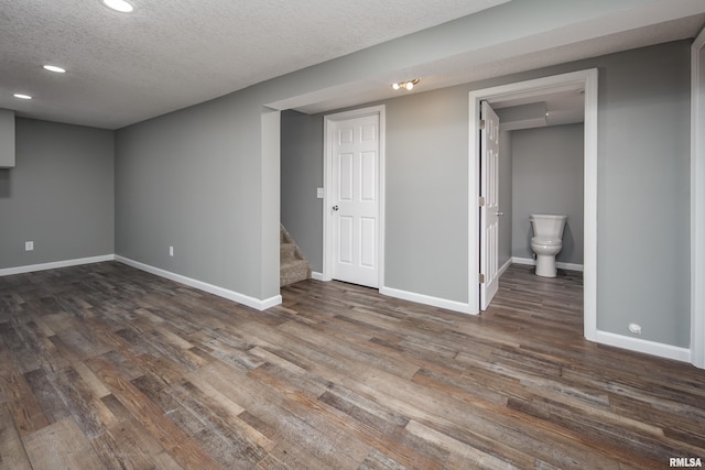 below grade area with baseboards, stairway, wood finished floors, a textured ceiling, and recessed lighting