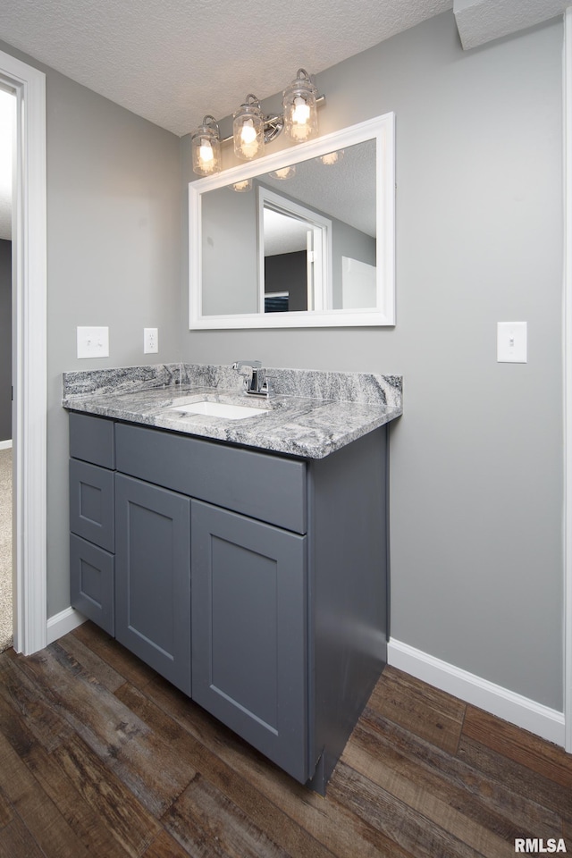 bathroom featuring a textured ceiling, wood finished floors, vanity, and baseboards