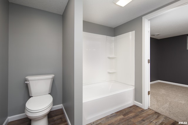 bathroom featuring a textured ceiling, wood finished floors, toilet, and baseboards