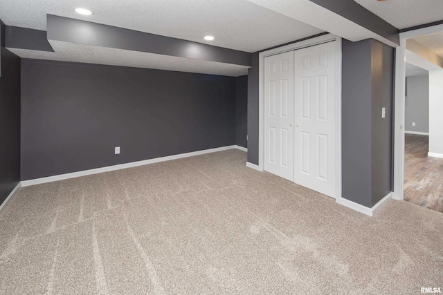 finished basement with carpet, a textured ceiling, baseboards, and recessed lighting