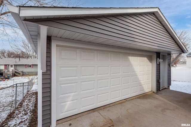 snow covered garage with fence