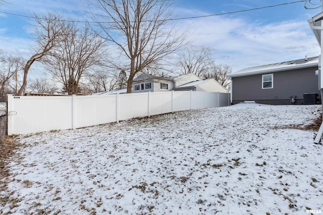 yard covered in snow featuring central AC unit and fence