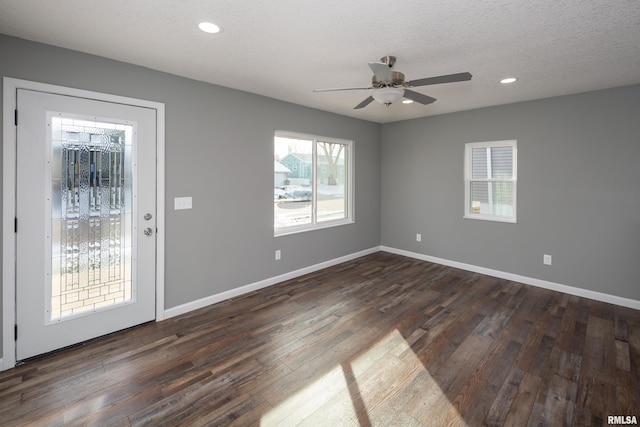 spare room with a textured ceiling, baseboards, dark wood-type flooring, and recessed lighting