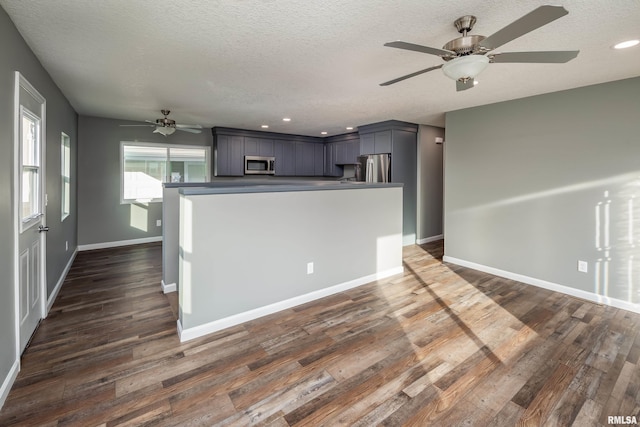 kitchen with baseboards, appliances with stainless steel finishes, dark wood finished floors, and a textured ceiling