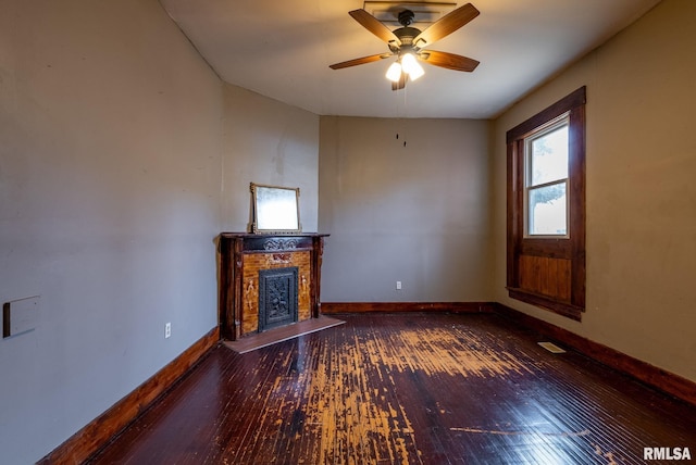 unfurnished living room with a ceiling fan, a fireplace with raised hearth, baseboards, and hardwood / wood-style flooring