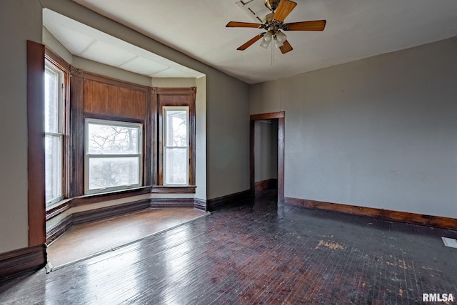 spare room featuring wood-type flooring, baseboards, and ceiling fan