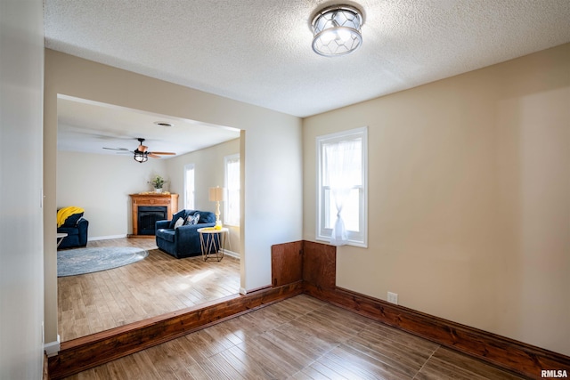 unfurnished living room featuring a textured ceiling, a fireplace, baseboards, and wood finished floors