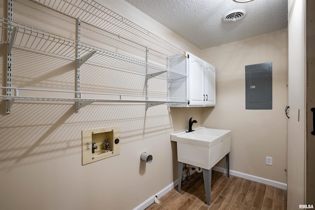 clothes washing area featuring hookup for a washing machine, wood finished floors, visible vents, cabinet space, and electric panel