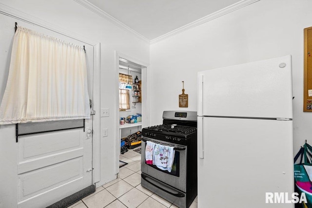 kitchen with gas range, light tile patterned floors, ornamental molding, and freestanding refrigerator