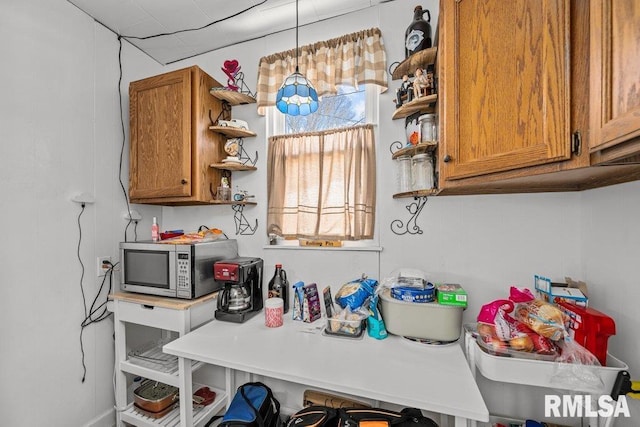 kitchen featuring brown cabinetry, stainless steel microwave, and open shelves