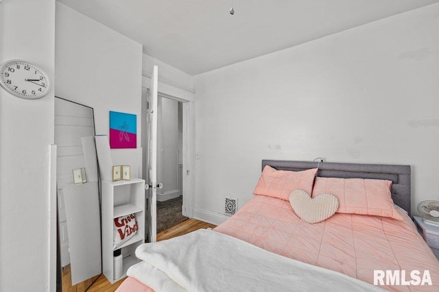 bedroom with wood finished floors, visible vents, and baseboards