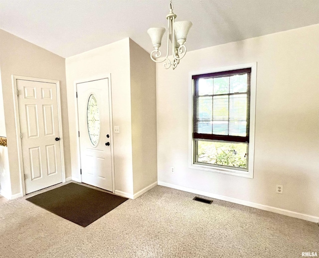 foyer featuring baseboards, visible vents, dark colored carpet, and a chandelier