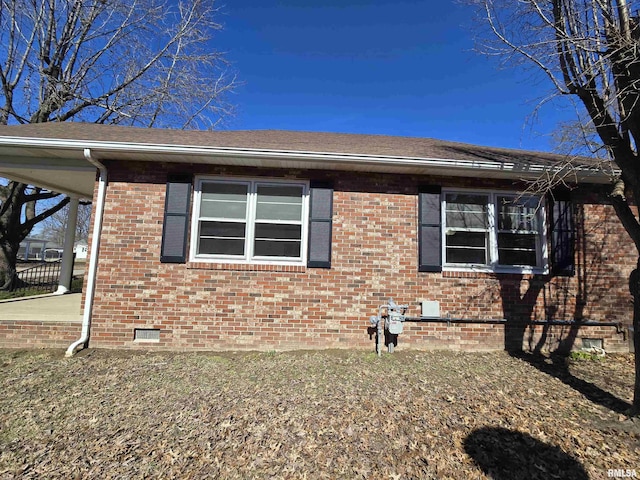 view of side of property featuring a shingled roof, crawl space, and brick siding