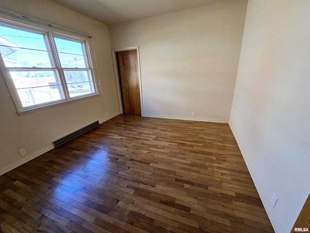 empty room with hardwood / wood-style flooring, baseboards, and a baseboard heating unit