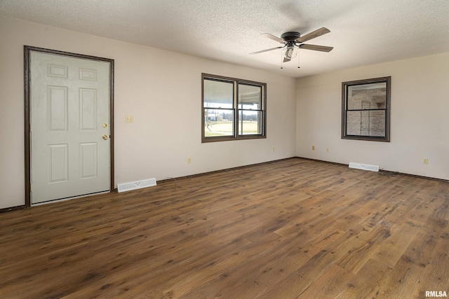 empty room with a ceiling fan, wood finished floors, visible vents, and a textured ceiling