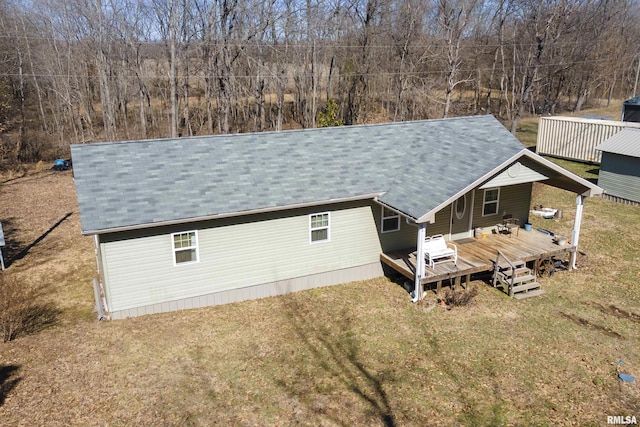 back of house with a deck, a shingled roof, and a lawn