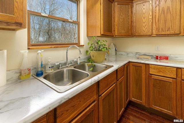 kitchen featuring brown cabinets, light countertops, a sink, and dark wood-type flooring