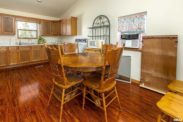 dining area featuring dark wood-type flooring, cooling unit, washer / clothes dryer, and vaulted ceiling