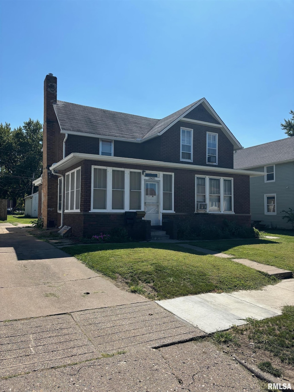 view of front facade with brick siding, a chimney, and a front yard