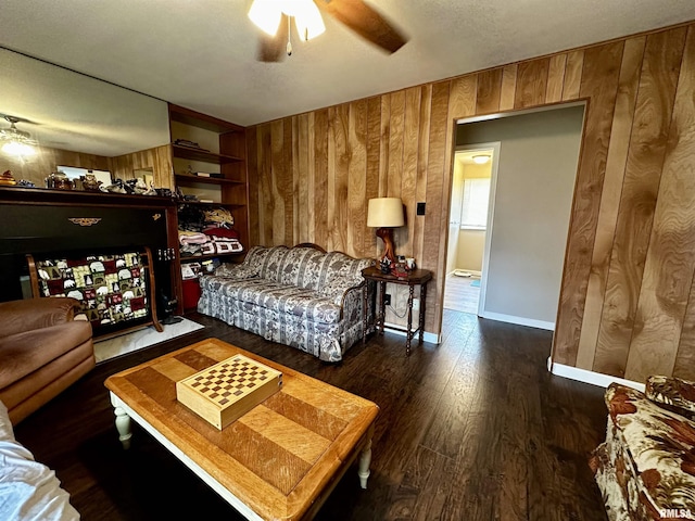 living room featuring a ceiling fan, wooden walls, and wood finished floors