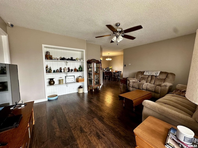 living area featuring a textured ceiling, built in shelves, ceiling fan with notable chandelier, and wood finished floors