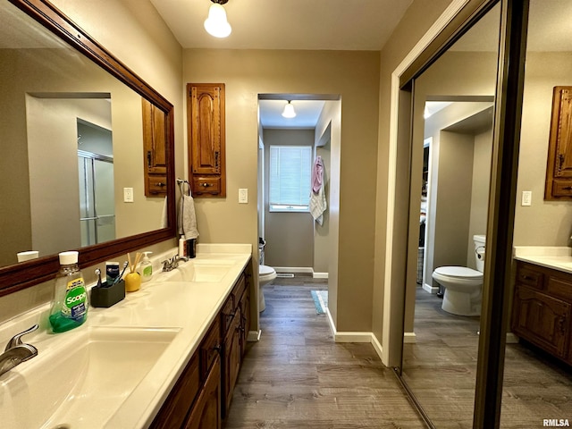 full bath featuring double vanity, a sink, toilet, and wood finished floors