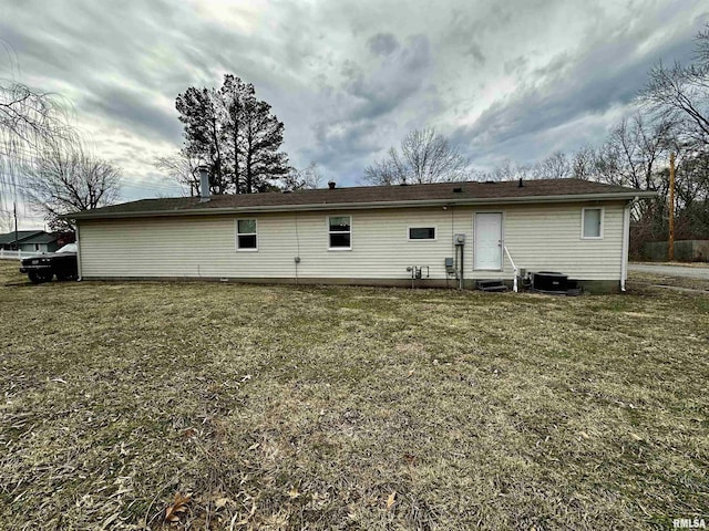 back of property with entry steps, central air condition unit, and a yard