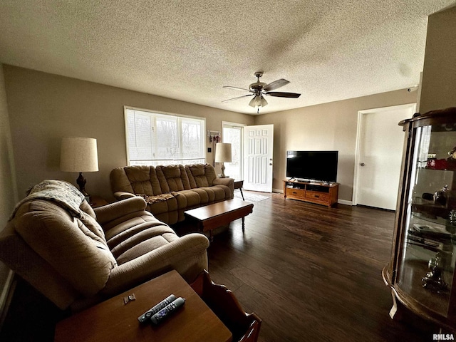 living area with dark wood-style flooring, ceiling fan, a textured ceiling, and baseboards