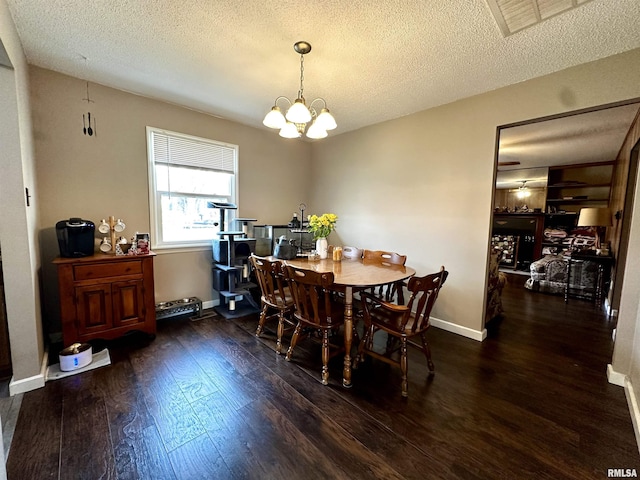 dining room featuring baseboards, a textured ceiling, hardwood / wood-style flooring, and a notable chandelier