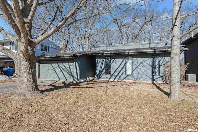 exterior space with central air condition unit, a garage, and concrete driveway