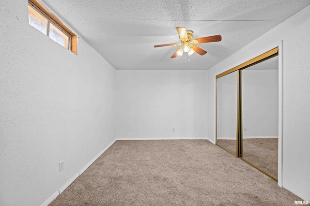 unfurnished bedroom featuring a textured wall, ceiling fan, carpet, a textured ceiling, and a closet