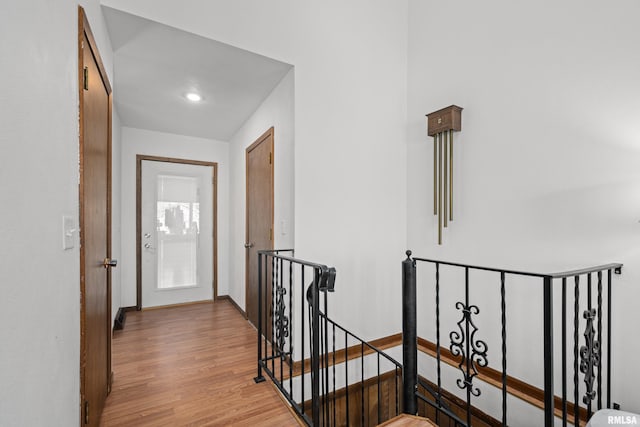 hall with baseboards, an upstairs landing, and light wood-style floors