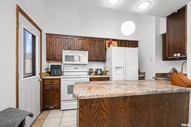 kitchen featuring white appliances, dark brown cabinetry, a peninsula, hanging light fixtures, and light tile patterned flooring