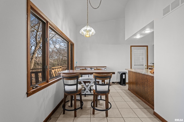 dining space featuring a high ceiling, visible vents, baseboards, and light tile patterned floors