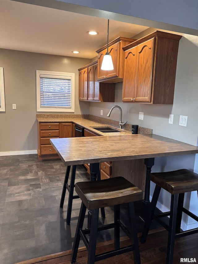 kitchen featuring recessed lighting, baseboards, a sink, a peninsula, and a kitchen breakfast bar